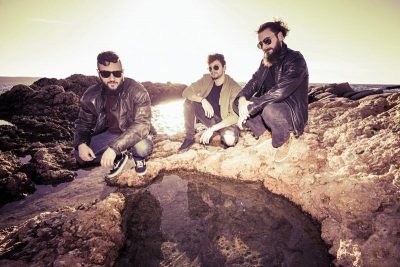 Die drei Mitglieder der Band Khirki auf Felsen an der Küste
