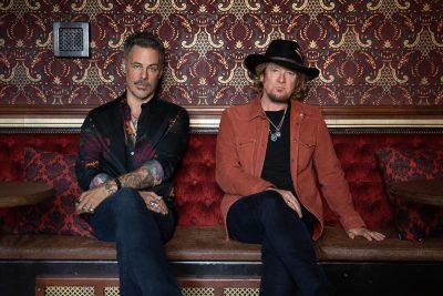 Die beiden Giatrriscten Richie Kotzen und Adrian Smith sitzen auf einem Sofa