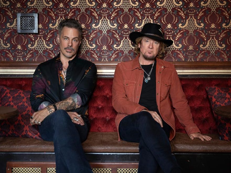 Die beiden Giatrriscten Richie Kotzen und Adrian Smith sitzen auf einem Sofa